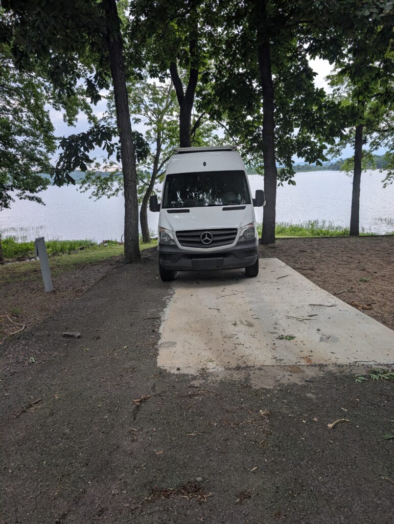 Our Sprinter at a lakeside campsite